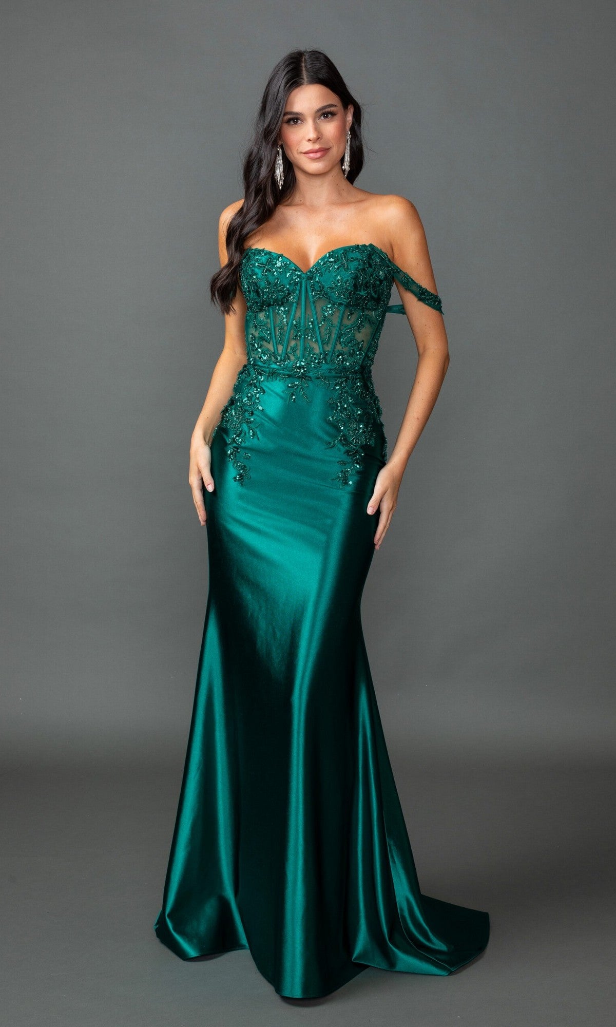 A woman models the Long Prom Dress: Dancing Queen 4540—a fitted, off-the-shoulder emerald satin mermaid gown with sequin lace and floral details—posed against a plain gray background.